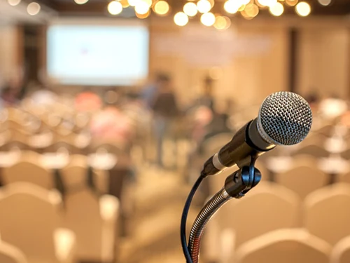 A microphone standing on a stage with an auditorium in the background